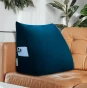Ein marineblaues Rückenstützkissen, das sich vom Hintergrund eines eleganten karamellfarbenen Ledersofas abhebt.