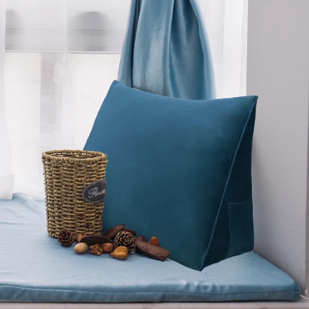 Auf einer gemütlich arrangierten Fensterbank liegt ein marineblaues Keilkissen – perfekt zum Lesen.