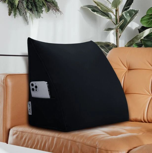 Vor dem Hintergrund eines eleganten Sofas aus karamellfarbenem Leder ist ein schwarzes Rückenstützkissen zu erkennen.