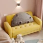Ein großes, halbkreisförmiges Kissen in Grau mit einem 3D-Mondmotiv (Krater) liegt auf einem kleinen, gesteppten, gelben Sofa.