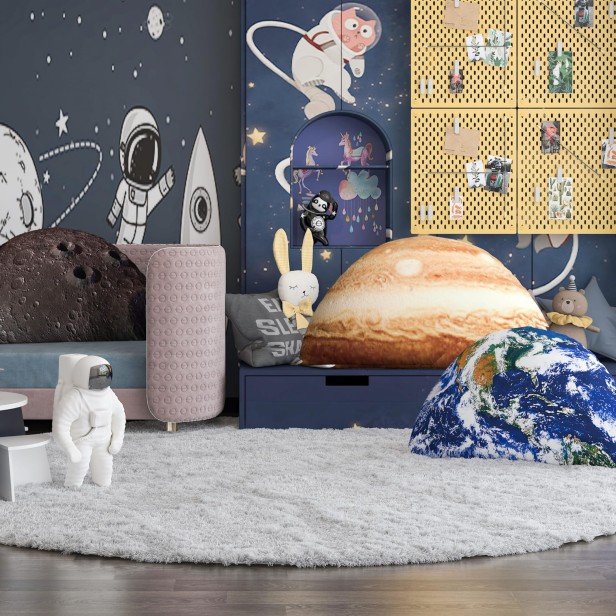 Ein Kinderzimmer, das im Weltraum-Stil dekoriert ist, mit einem großen, runden, grauen Mondkissen, einem Jupiterkissen und einem Erdkissen.