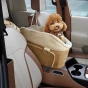 Der entzückende kleine Hund reist sicher und komfortabel in einem luxuriösen braun-beigen Autositz auf dem Beifahrersitz des Fahrzeugs.