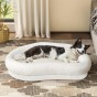 Ein Hund liegt bequem in einem großen, ovalen Cloud-Hundebett in hellbeige.