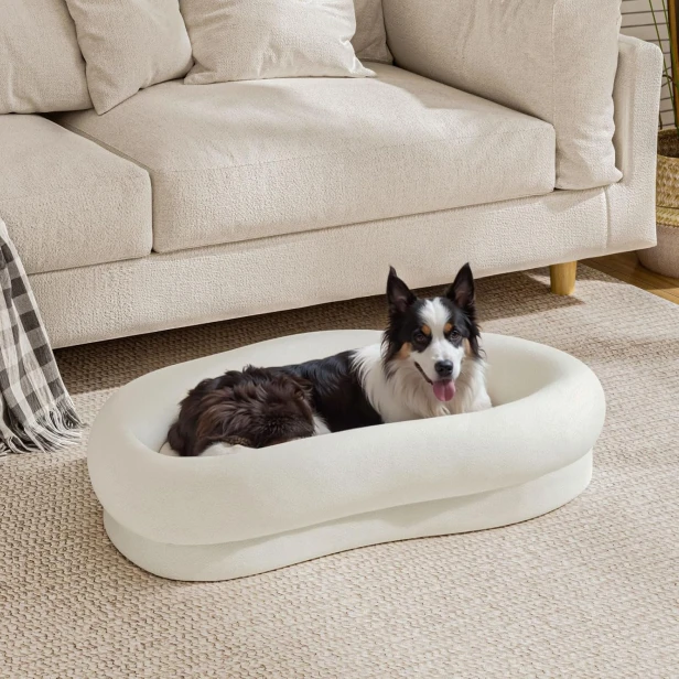 Ein elegantes, ovales Hundebett für mittelgroße und große Hunde mit dicken Rändern. Die cremefarbene Ausführung passt perfekt in ein modernes Wohnzimmer.