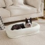 Ein elegantes, ovales Hundebett für mittelgroße und große Hunde mit dicken Rändern. Die cremefarbene Ausführung passt perfekt in ein modernes Wohnzimmer.