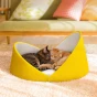 Zwei Katzen, eine getigerte und eine rote, schlafen zusammen in einem weichen gelben Katzenbett mit erhöhtem Muschelrand.