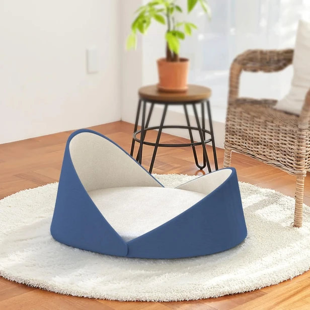 Luxuriöses Muschel-Katzenbett - Blau, platziert in einem hellen, stilvollen Interieur.