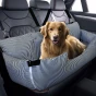 Der rote Hund liegt in einem großen, schwarz-weiß gestreiften Autobett, das mit Gurten an den Kopfstützen der Rückbank befestigt ist.