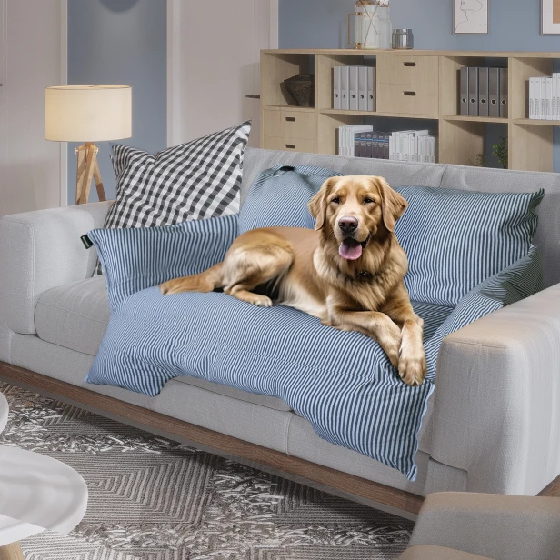 Der Hund liegt auf einem grauen Sofa, das mit einer blau-weiß gestreiften, wasserdichten Hundedecke/einem Hundebett abgedeckt ist, um die Möbel vor Haaren und Schmutz zu schützen.