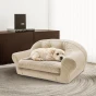 Ein Welpe liegt auf einem luxuriösen, beigefarbenen, gesteppten Hundesofa in einem eleganten Interieur.