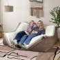 Zwei lächelnde Frauen entspannen sich auf einem großen, braun-beigen modularen Lounge-Sofa mit weichem, geripptem Stoff.