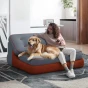 Eine Frau und ihr Golden Retriever sitzen zusammen in einem modernen, zweisitzigen Modulsessel in Grau mit orangefarbenen Akzenten. Eine modulare Chaiselongue, die sich in ein 3-Wege-Bett verwandeln lässt.