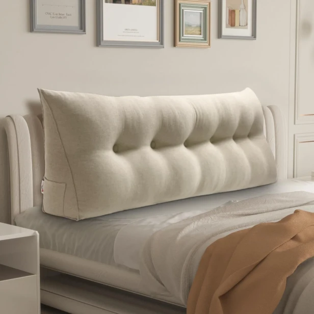 Beiges dreieckiges Lesekissen, Schlafzimmerdekoration auf dem Bett.