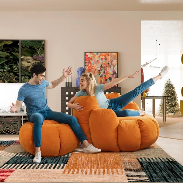 Ein junges Paar sitzt auf kürbisförmigen Poufs.