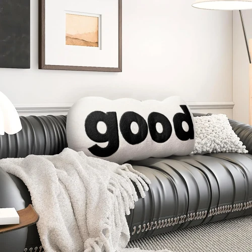Plüschiges schwarzes Lesekissen. Arrangiert im Wohnzimmer auf dem Sofa.