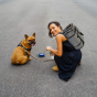 Frau mit Haustier-Reisetasche auf dem Rücken und Hund.
