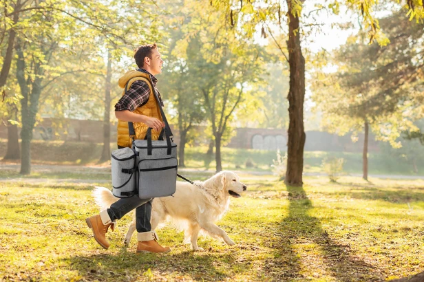 Mann führt seinen Hund mit einer Haustier-Reisetasche aus