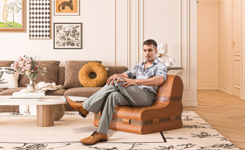 Ein Mann sitzt in einem Wohnzimmer auf einem Sofa mit dekorativen Lederriemen.