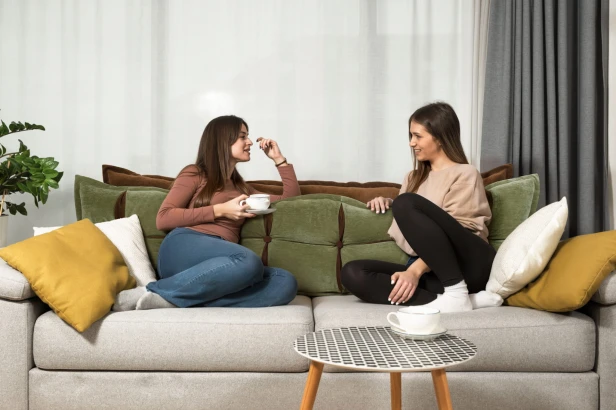 Frauen lehnen an einem Sofa mit einer grün-orangefarbenen Kopfstütze mit Stauraumkissen.