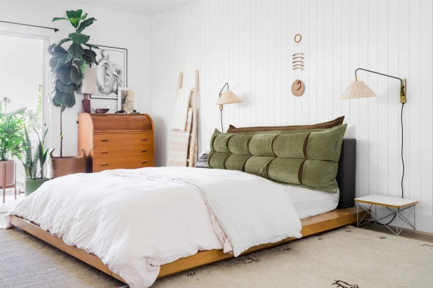 Grünes und oranges Kopfstützkissen mit Stauraum, Schlafzimmer-Arrangement auf dem Bett.