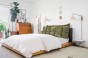 Grünes und oranges Kopfstützkissen mit Stauraum, Schlafzimmer-Arrangement auf dem Bett.