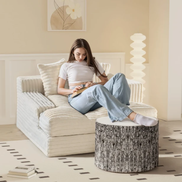 Eine Frau, die ihre Beine auf dem ovalen Hocker „Warm Tree Geometric“ ausruht.