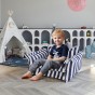 Junge sitzt auf einem Multifunktionssofa mit Bodenkissen im Kinderzimmer.
