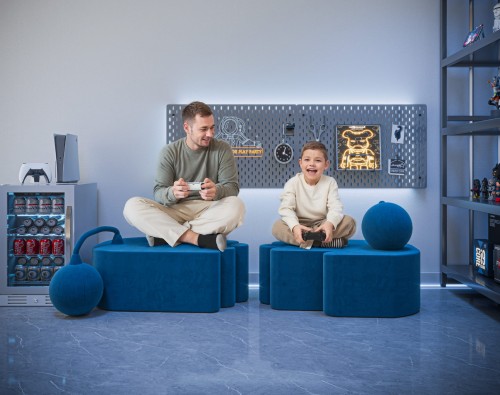 Ein Mann sitzt mit einem Jungen auf zwei modernen blauen Poufs.