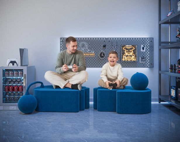 Ein Mann sitzt mit einem Jungen auf zwei modernen blauen Poufs.
