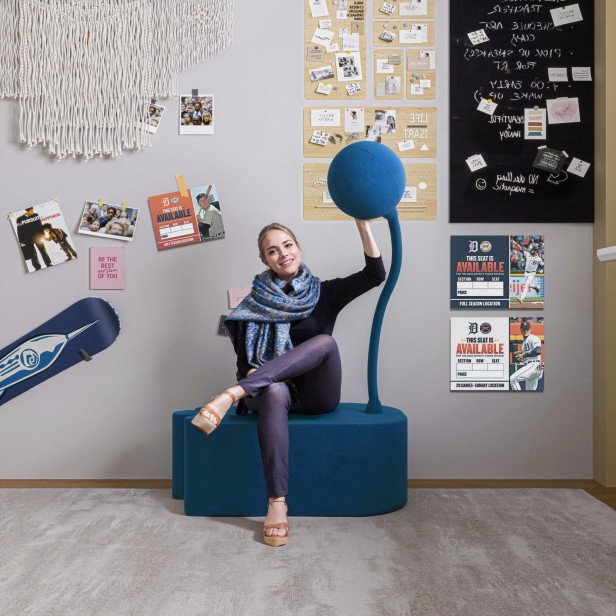 Frau sitzt auf einem modernen blauen Pouf.