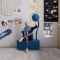 Frau sitzt auf einem modernen blauen Pouf.