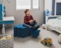 Junge sitzt und spielt auf einem modernen blauen Pouf.