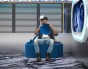 Mann sitzt und spielt auf einem modernen blauen Pouf.