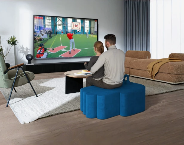 Ein Paar sitzt und spielt auf einem modernen blauen Pouf.