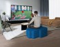 Ein Paar sitzt und spielt auf einem modernen blauen Pouf.