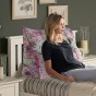Frau lehnt sich an ein Bett mit einem rosa Jacquard-Knopfkissen
