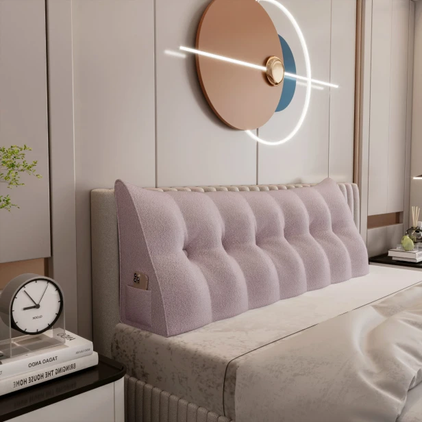 Dreieckiges, plüschiges, rosafarbenes Kissen, arrangiert im Schlafzimmer auf dem Bett.