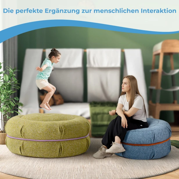 Ein Mädchen springt auf einen Pouf, eine Frau sitzt daneben auf einem blauen Makkaroni-Pouf.