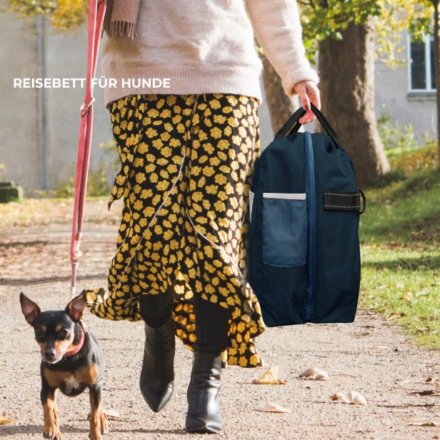 Frau mit Hund trägt ein tragbares Reisebett für Haustiere