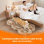Ein Mann ruht sich im Bett aus und ein Golden Retriever liegt auf einem flauschigen Kunstfellteppich.