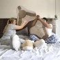 Ein paar Erwachsene veranstalten im Bett eine lustige Kissenschlacht mit großen, geometrischen Kissen.