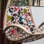 Vielseitiges Lesekissen mit Waldmotiv, arrangiert auf einem Korbsessel auf der Terrasse.