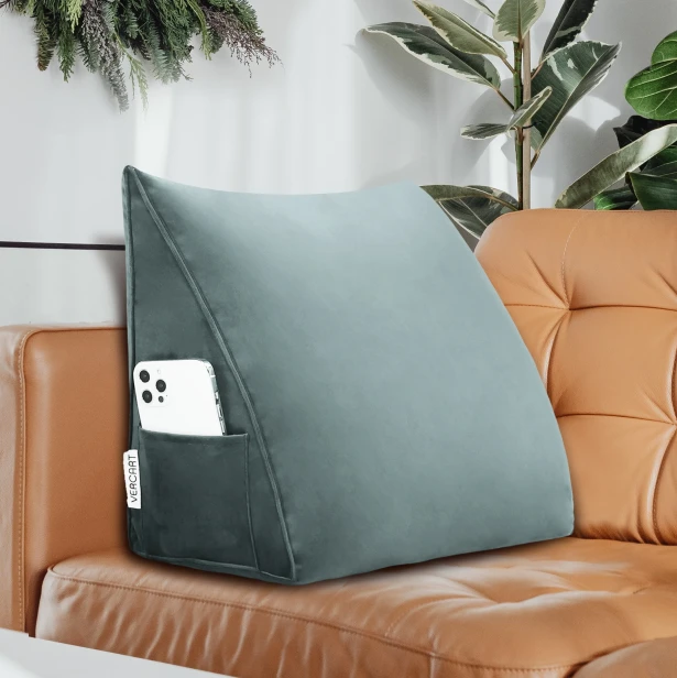 Vor dem Hintergrund eines eleganten Sofas aus karamellfarbenem Leder ist ein graues Rückenstützkissen zu erkennen.